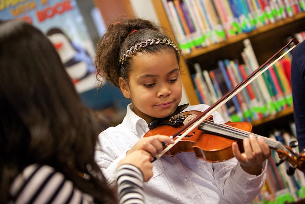 A young student playing violin in a GRS education program